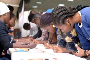 Participants registering by the registration stand at the #IYD2016NG event.
